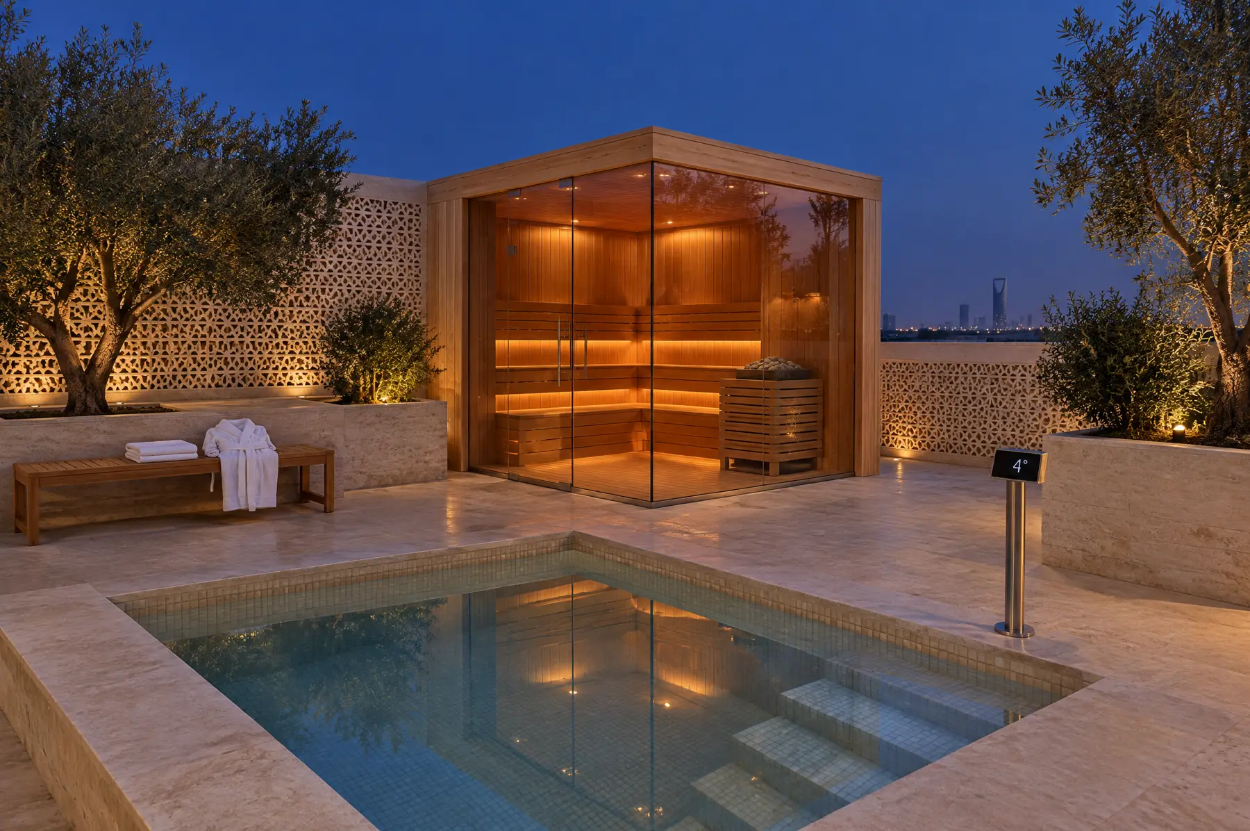 Villa-compound terrace at blue hour with a copper-lit glass-cornered sauna, a square cold plunge pool mirroring the sky, a limestone screen and olive trees