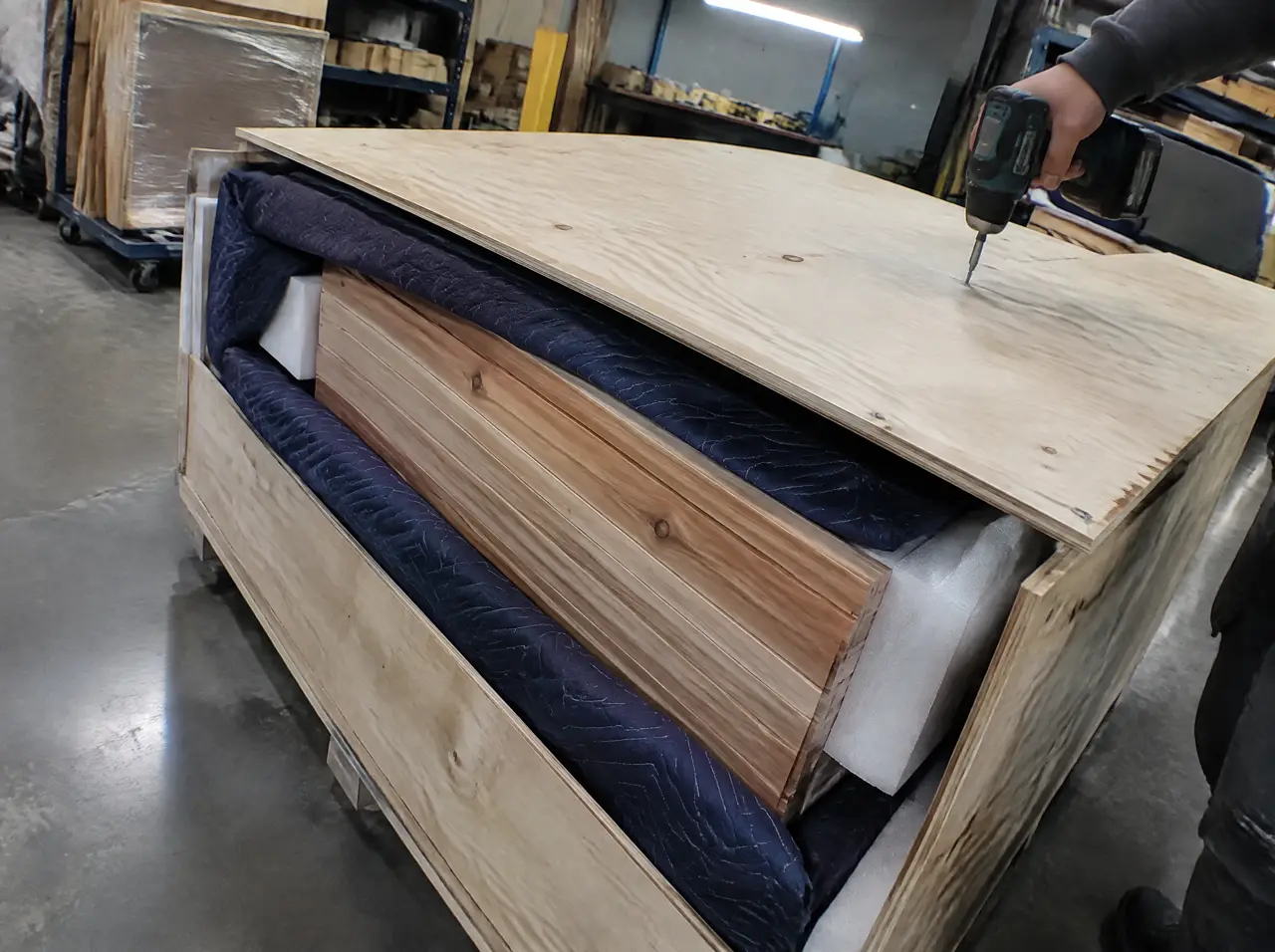 A plywood crate with cedar sauna wall panels wrapped in blankets and foam corners